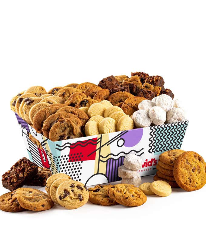 A colorful box filled with an assortment of David's cookies, including chocolate chip, sugar, oatmeal raisin, and powdered sugar cookies. Brownies and additional cookies are arranged around the box.