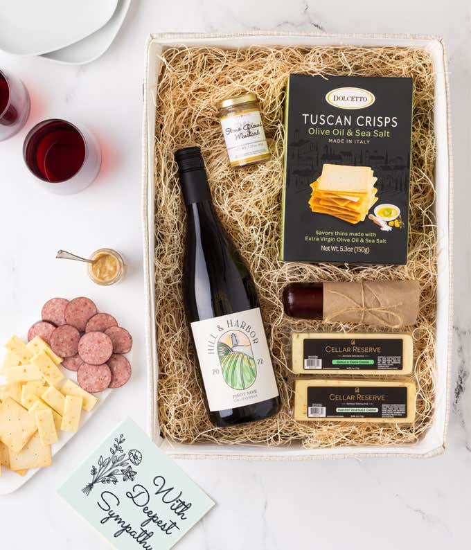 A gift box with a bottle of California Pinot Noir, two types of cheese, 