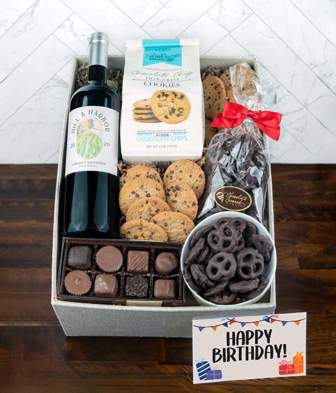 a gift box full of decadent treats with a Birthday message card.  Contents include: a bottle of California Pinot Noir, a bag of milk chocolate pretzel, a box of mini chocolate chip cookies, and a 4-ounce box of assorted chocolates.