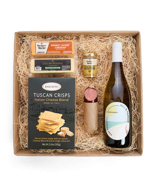 A gift box with a bottle of California Chardonnay, two types of cheese, crackers, stone-ground mustard, and a summer sausage.