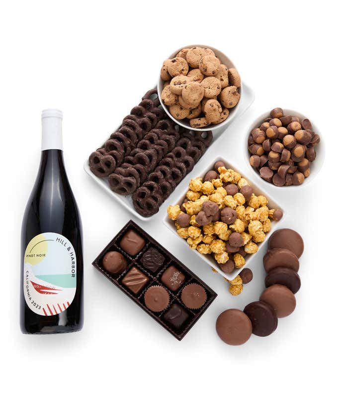 A gift set featuring a bottle of California Pinot Noir with chocolate pretzels, caramel popcorn, mini cookies, chocolate peanut butter buckeyes, 6 chocolate-covered Oreos and a box of assorted chocolates for a luxurious touch.