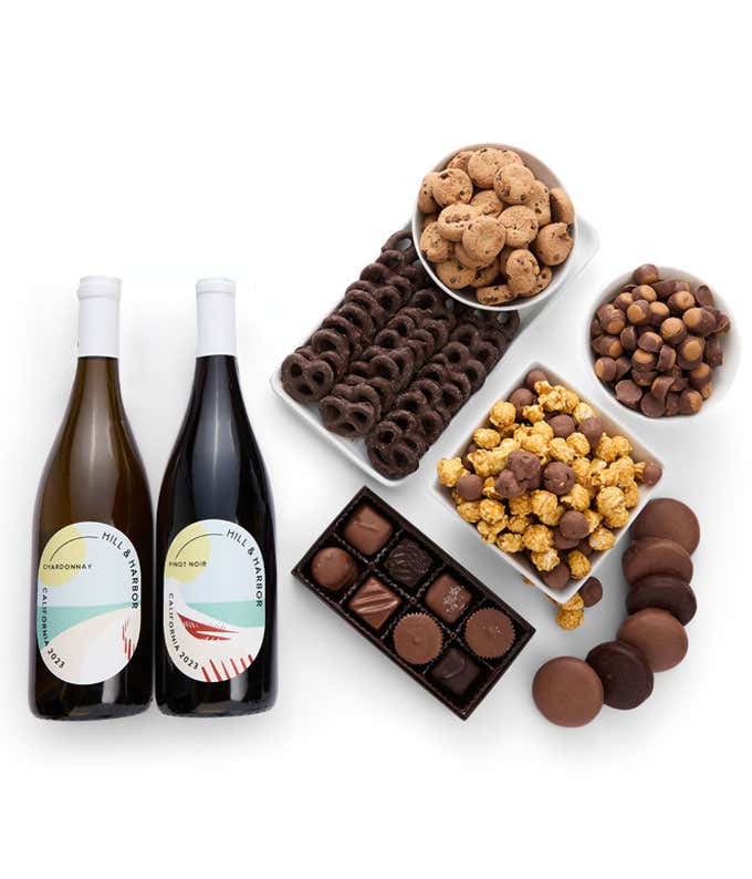 A gift set with 2 bottles of wine - red and white, paired with chocolate pretzels, caramel popcorn, mini cookies, chocolate peanut butter buckeyes, six chocolate-covered Oreos, and a box assorted chocolates.