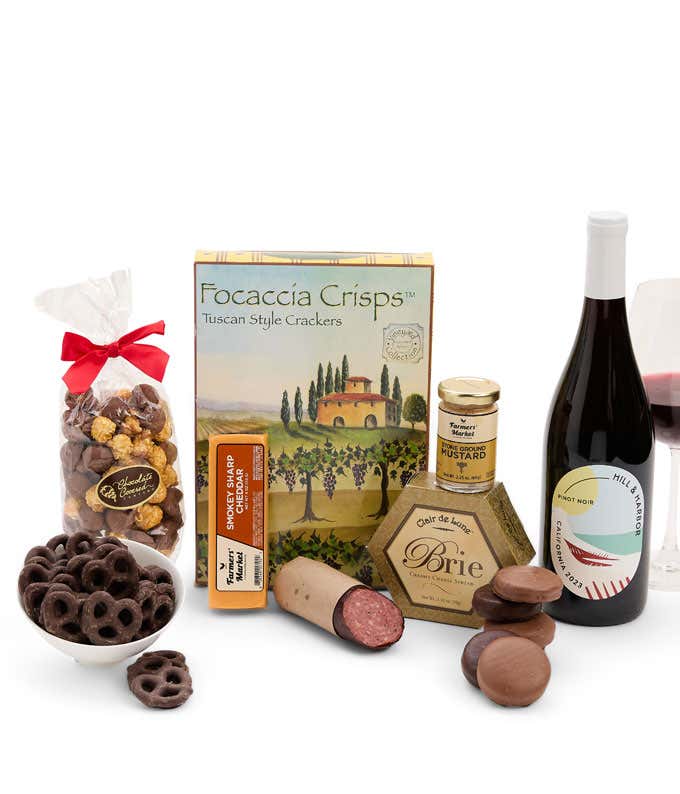 A gift set featuring a bottle of California Pinot Noir, focaccia crisps, 2 cheeses, mustard, summer sausage, caramel popcorn, chocolate pretzels, and 6 chocolate-covered Oreos for a sweet and savory gourmet experience.