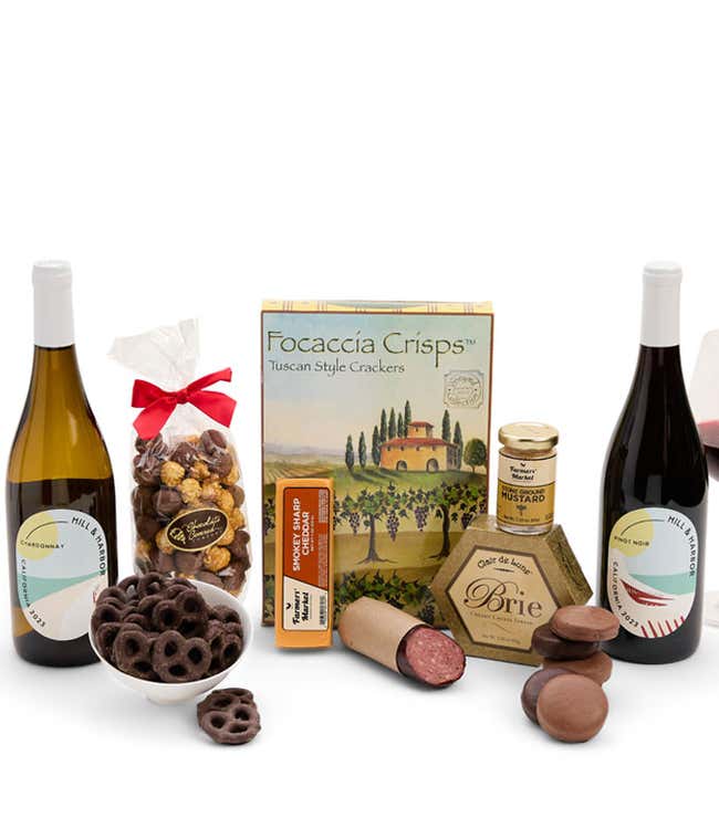 A gift set featuring two bottles of Hill &amp; Harbor wine - white and red, focaccia crisps, 2 cheeses, mustard, summer sausage, caramel popcorn, chocolate pretzels, and 6 chocolate-covered Oreos for a sweet and savory gourmet experience.