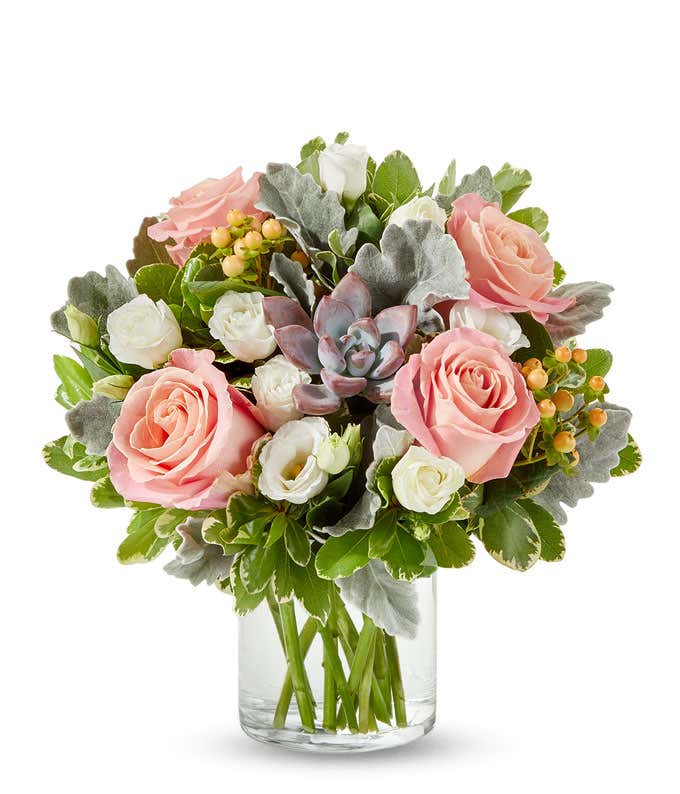 A charming floral arrangement featuring pink roses, white lisianthus, peach berries, a succulent cutting, all beautifully arranged in a glass vase, with an option for personalization. This vibrant mix creates a stunning and unique display.