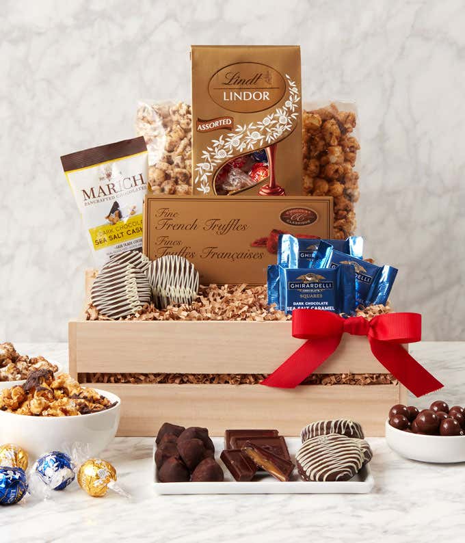 A gourmet gift basket with assorted chocolates and treats, including Lindt Lindor truffles, Marich dark chocolate sea salt caramels, French truffles, Ghirardelli dark chocolate sea salt caramel squares, chocolate-covered cookies, caramel popcorn, and more