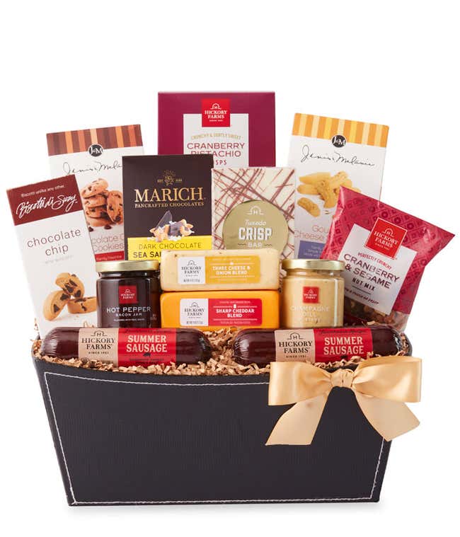 A  black gift basket with two packs of sausage, a wheel of gouda cheese, a block of cheddar cheese, a jar of honey pineapple mustard, a jar of hot &amp; sweet mustard, and fig chutney, a box of chocolate chip mini biscotti, chocolate chip cookies, toffee pret