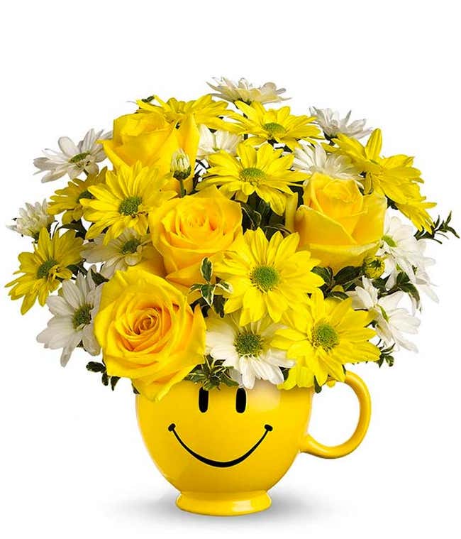 Yellow roses and bright daisies in a yellow smiley face mug